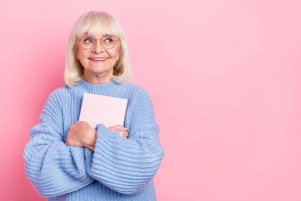 Retrato de atraente alegre criativo inteligente mulher de cabelos grisalhos abraçando espaço cópia livro isolado sobre cor pastel rosa fundo — Fotografia de Stock