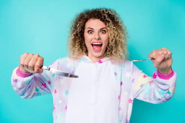 Foto de impressionado milenar curly hairdo senhora comer desgaste pijama isolado no fundo azul — Fotografia de Stock