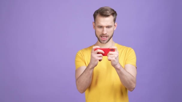 Emocionado chico joven jugar gadget puño hasta aislado vívido color fondo — Vídeos de Stock
