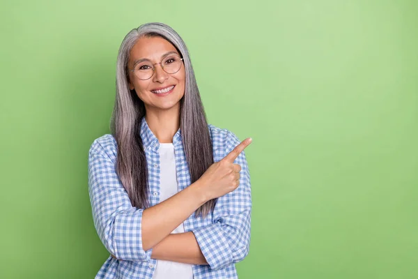 Fénykép az optimista idősebb szürke frizura hölgy index promo kopás szemüveget kockás ing elszigetelt zöld színű háttér — Stock Fotó
