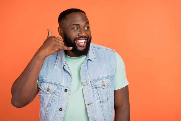 Photo of funny dreamy guy wear denim vest phone gesture empty space isolated orange color background — Stock Photo, Image