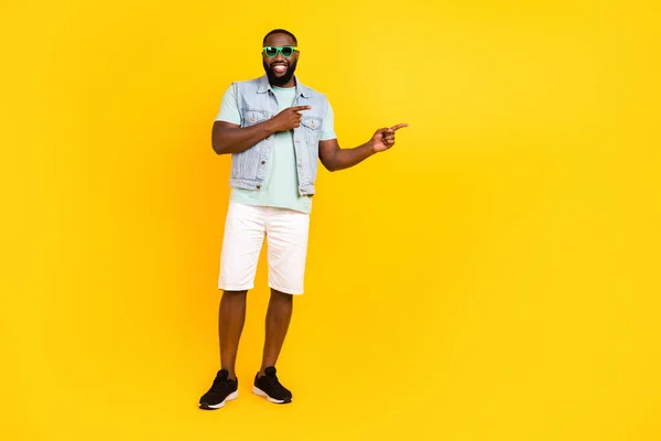 Full längd kroppsstorlek bild av attraktiv glad kille hipster visar kopia utrymme isolerad över ljusa gula färg bakgrund — Stockfoto