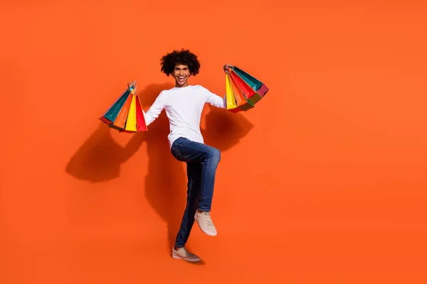 Foto van vrij gelukkig man gekleed wit shirt stijgende shoppers lege ruimte geïsoleerde oranje kleur achtergrond — Stockfoto