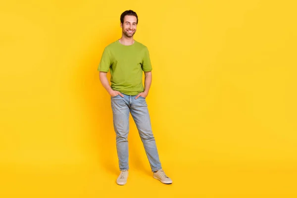 フル長さの写真素敵なブルネットヘアドミレニアル男スタンド摩耗tシャツジーンズの靴は黄色の色の背景に隔離 — ストック写真
