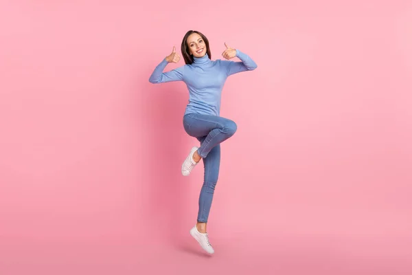 믿을 만 한 홍보 담당자가 점프하는 사진, 엄지손가락 인상 승인률 파란 터틀넥외진 핑크 색 배경을 착용 — 스톡 사진