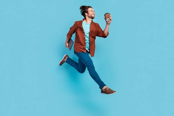 Profil pleine grandeur photo de brunet impressionné jeune homme courir avec ordinateur portable tasse porter lunettes chemise pantalon chaussures isolé sur fond bleu — Photo