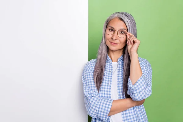 Foto di pensare anziano capelli bianchi signora vicino poster indossare occhiali camicia a scacchi isolato su sfondo di colore verde — Foto Stock