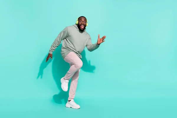 Volledige lengte lichaam grootte uitzicht van vrolijke aantrekkelijke man dansen moderne hip hop ritme geïsoleerd over glans teal turquoise kleur achtergrond — Stockfoto