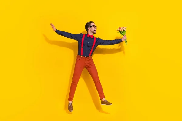 Bilder i full størrelse av unge menn som hopper opp, gir tulipanhøytid isolert på gul bakgrunn. – stockfoto