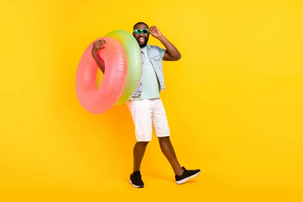 Plná délka tělo velikost pohled na atraktivní bláznivý veselý chlap nesoucí gumový kruh izolované přes jasně žluté barvy pozadí — Stock fotografie