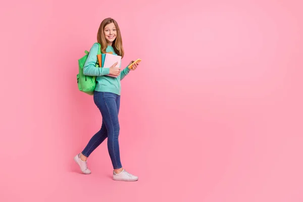 Foto de menina doce usar camisola turquesa segurando material escolar dispositivo vazio espaço isolado cor-de-rosa fundo — Fotografia de Stock