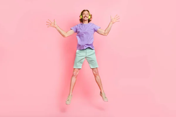 Teljes hosszúságú testméret kilátás vonzó vidám srác ugrás hallgatás dal hit szórakozás elszigetelt rózsaszín pasztell szín háttér — Stock Fotó