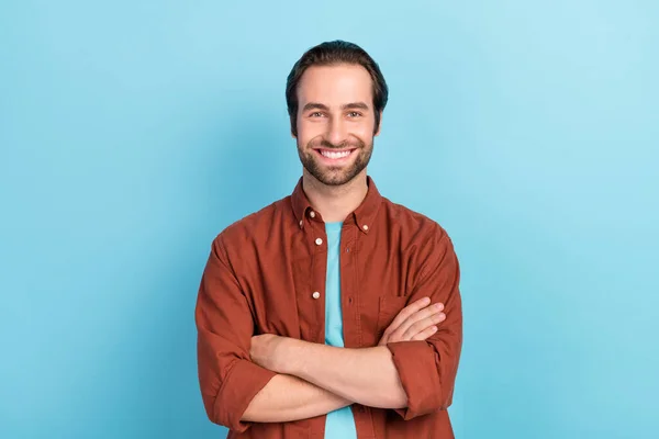 Foto de bonito peinado marrón millennial chico cruzó brazos usar camisa aislada sobre fondo de color azul — Foto de Stock