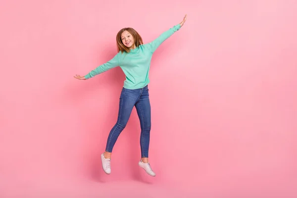 Photo excitée écolière ludique habillée sarcelle pull bras côtés sautant espace vide isolé couleur rose fond — Photo