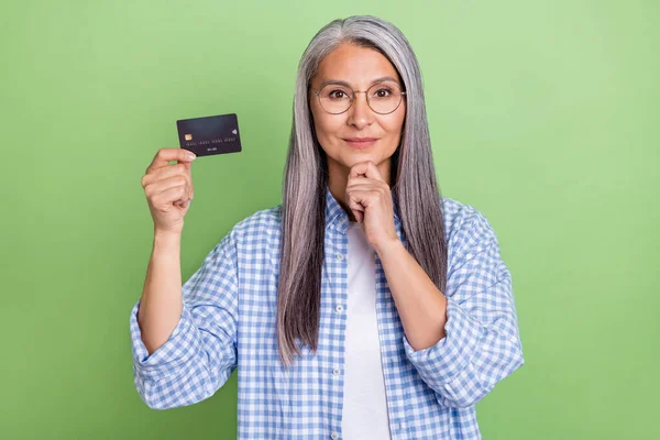 Foto di intelligente invecchiato capelli bianchi signora tenere carta usura occhiali camicia a quadri isolato su sfondo di colore verde — Foto Stock