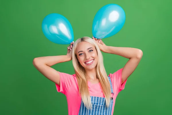 Foto de adorável engraçado agradável senhora segurar dois balões fazer orelhas desgaste listrado geral isolado cor verde fundo — Fotografia de Stock