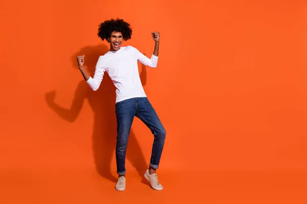 Foto de cara feliz animado usar camisa branca levantando punhos espaço vazio isolado cor laranja fundo — Fotografia de Stock