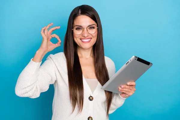 Foto av vacker dam klädd vit kofta glasögon skriva modern gadget visar okey isolerad blå färg bakgrund — Stockfoto