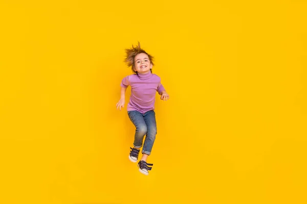 Full size foto di buon umore allegro piccolo ragazzo giocoso saltando su scherzare in giro isolato su sfondo di colore giallo — Foto Stock