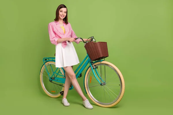 Foto em tamanho completo de sorrir menina bonita viajando veículo de bicicleta tempo livre isolado no fundo de cor verde — Fotografia de Stock