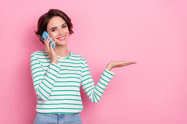 Portret van aantrekkelijke vrolijke meisje vasthouden op palm kopieerruimte d advertentie praten op telefoon geïsoleerd over roze pastel kleur achtergrond — Stockfoto