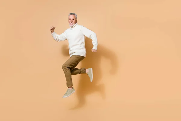 Longitud completa cuerpo tamaño vista de atractivo alegre hombre saltando corriendo rápido aislado en beige pastel color fondo —  Fotos de Stock