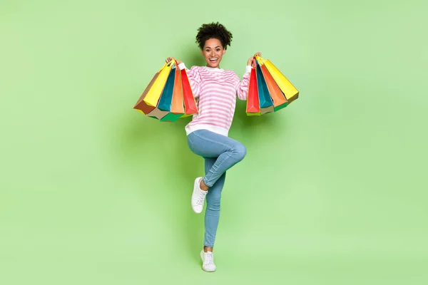 Foto di eccitato divertente felice signora tenere i pacchetti negozio indossare camicia a righe jeans isolato colore verde sfondo — Foto Stock