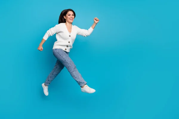 Foto av söt charmig kvinna bära vit kofta kör snabbt hoppa hög isolerad blå färg bakgrund — Stockfoto