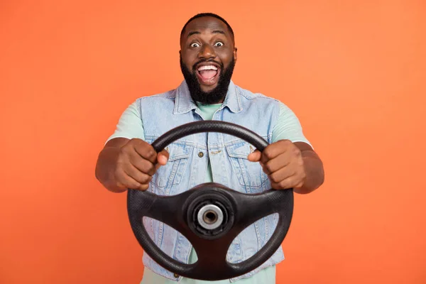 Photo of excited african guy dressed jeans waistcoat riding auto open mouth isolated orange color background — Stock Photo, Image