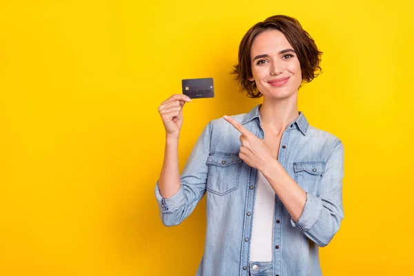 Фотографія молодої красивої дівчини вказує на палець кредитну картку виберіть рекламну пропозицію ізольовану на жовтому кольорі — стокове фото