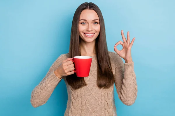 Портрет привлекательной веселой здоровой девушки, пьющей травяной чай, показывая ОК-знак изолированы на ярко-голубом фоне цвета — стоковое фото