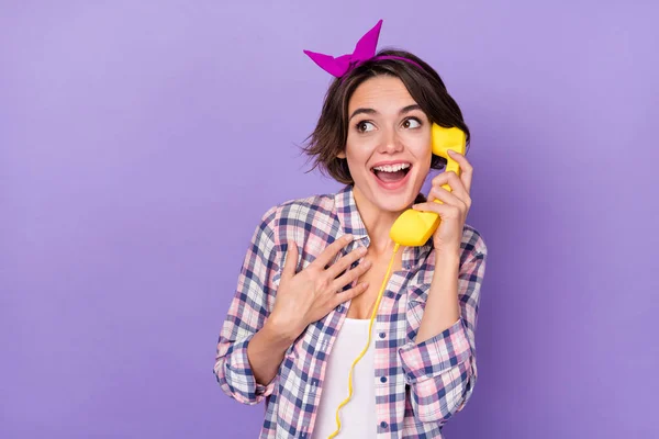 Foto van opgewonden grappige vrouw dragen geruite shirt praten telefoon op zoek lege ruimte geïsoleerde violette kleur achtergrond — Stockfoto