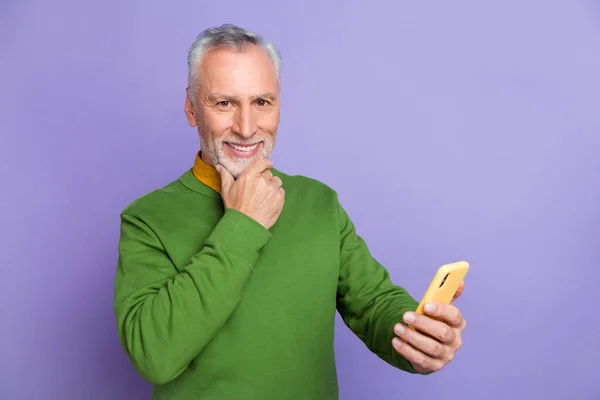 Photo of confident man pensioner dressed green pullover chatting modern gadget isolated purple color background — Stock Photo, Image