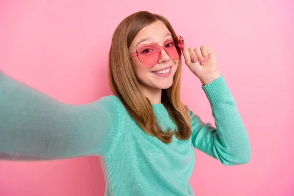 Foto van mooie school meisje gekleed teal pullover arm hart oogkledij opnemen zelf video geïsoleerde roze kleur achtergrond — Stockfoto