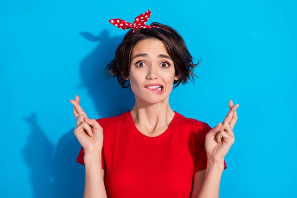 Photo of sad young brunette lady bite lip wear red t-shirt hairband isolated on blue color background — Stock Photo, Image