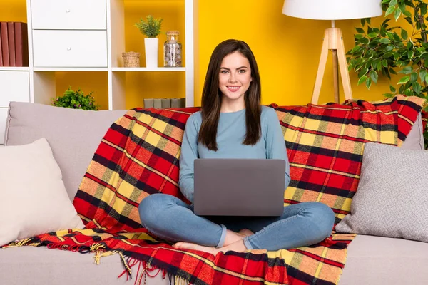 Plná velikost fotografie pozitivní hezká dáma sedět bosá gauč použití netbook izolované na žluté barvy pozadí — Stock fotografie