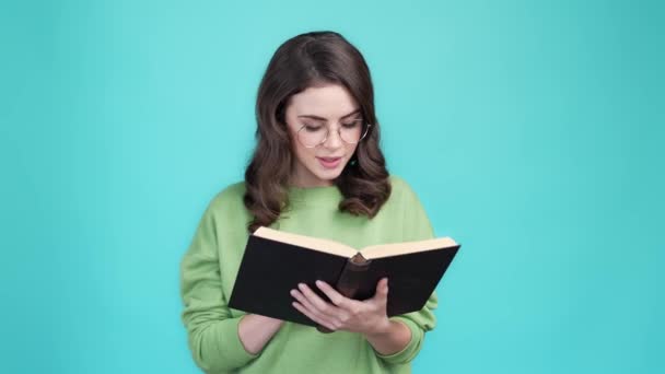 Smart Dame Akademikerin lesen Lehrbuch isoliert Cyan Farbe Hintergrund — Stockvideo