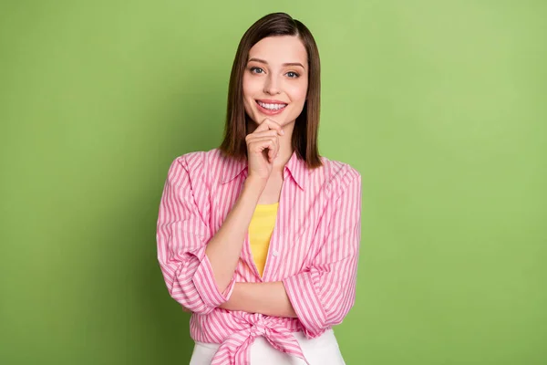 Retrato de una chica joven bastante femenina sonriente lluvia de ideas pensando usar camisa a rayas aislada sobre fondo de color verde —  Fotos de Stock