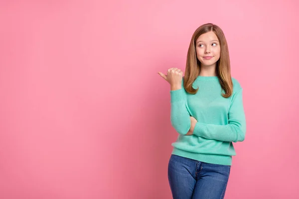 Fotografie zasněné sladké školní dívka oblečené teal pullover ukazující prázdný prostor izolované růžové barvy pozadí — Stock fotografie