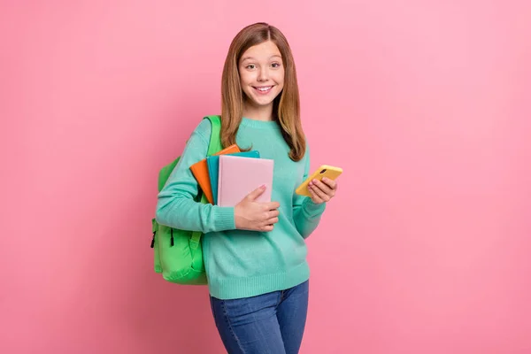 Güzel bir kızın, elinde okul malzemeleri tutan turkuaz süveter giydiği fotoğraf modern cihazın pembe arka planı. — Stok fotoğraf