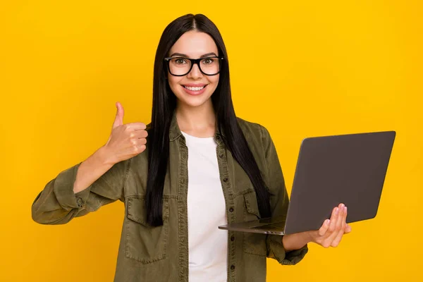 Фото крутой дамы тысячелетия держать ноутбук вверх носить очки рубашку цвета хаки изолированы на желтом фоне — стоковое фото