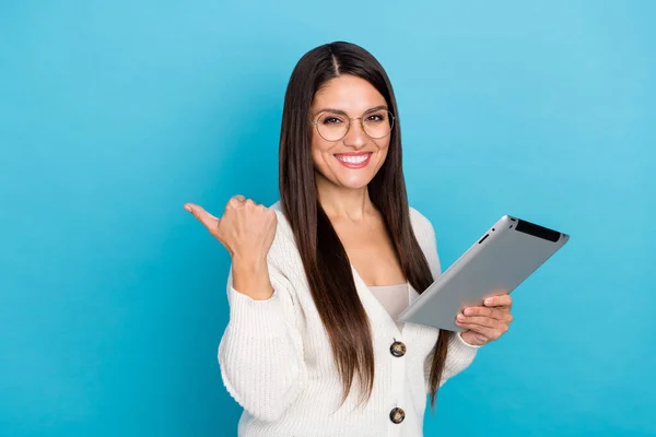 Foto de mulher doce desgaste branco cardigan óculos apontando espaço vazio moderno dispositivo isolado azul cor de fundo — Fotografia de Stock