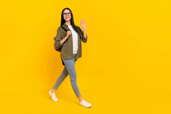 Corpo inteiro foto de impressionado milenar senhora ir onda desgaste saco óculos camisa jeans calçado isolado no fundo amarelo — Fotografia de Stock