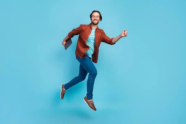 Ganzes Foto von flippigen Brunet Millennial Kerl laufen mit Laptop tragen Brille Hemd Hose Schuhe isoliert auf blauem Hintergrund — Stockfoto
