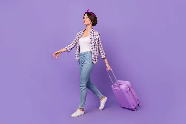 Foto lateral de perfil de tamaño completo de la joven dama caminar bolsa vuelo aeropuerto viaje aislado sobre fondo de color púrpura —  Fotos de Stock