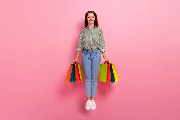 Photo of cute charming lady dressed green shirt jumping high holding bargains isolated pink color background — Stock Photo, Image