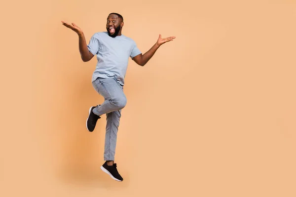 Full längd kroppsstorlek bild av attraktiv glad lycklig kille hoppa glädje kopia utrymme isolerad över beige pastell färg bakgrund — Stockfoto