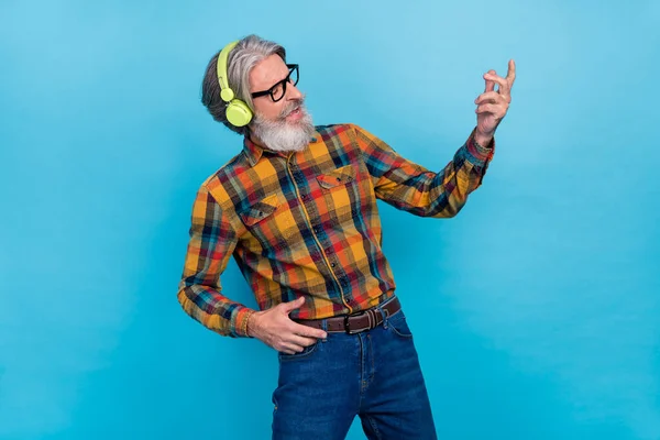 Фото крутого чоловіка пенсіонер одягнений в картаті сорочки окуляри прослуховування музики грає на гітарі ізольований синій колір фону — стокове фото