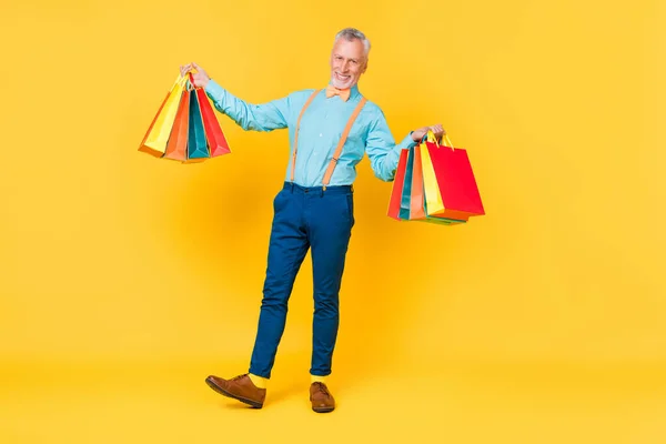 Foto von flippigen süßen Kerl Rentner gekleidet Krickente Hemd Fliege halten Shopping-Schnäppchen isoliert gelbe Farbe Hintergrund — Stockfoto