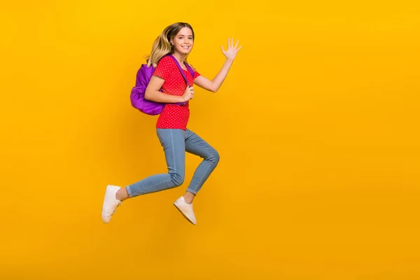 Full kropp profil sida foto av ung flicka hoppa våg hi semester energisk hålla väska isolerad över gul färg bakgrund — Stockfoto